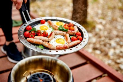 Sausage, eggs and tomatoes cooking in the Cobb fry pan on garden decking