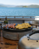 Cobb Supreme portable charcoal cooker grilling on the deck of a boat