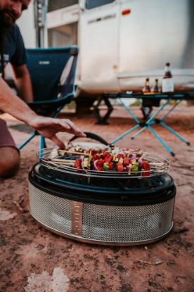 Cobb Supreme portable charcoal cooker grilling kebabs outside of motorhome