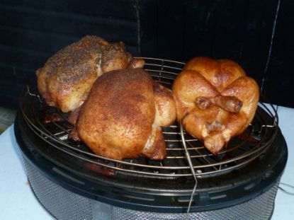 Three chickens roasting on Cobb Supreme portable charcoal cooker